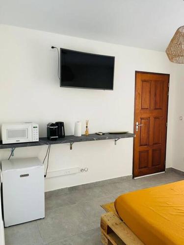 een kamer met een bed en een televisie aan de muur bij Paisible studio tout confort in Matoury