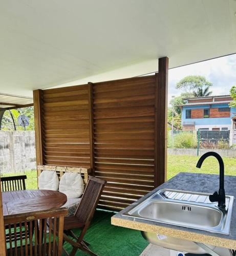 een keuken met een wastafel en een tafel en stoelen bij Paisible studio tout confort in Matoury