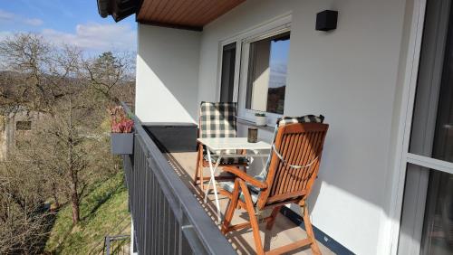 un balcón con 2 sillas y una mesa. en Zimmer im Herzen Gößweinsteins en Gößweinstein