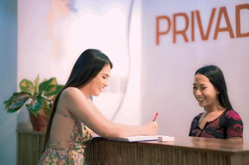 two women standing at a desk writing in a notebook at Privada Villa Siargao in General Luna