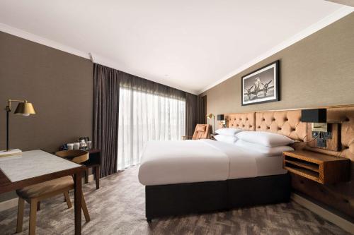 um quarto de hotel com uma cama grande e uma secretária em DoubleTree by Hilton Hotel Newcastle International Airport em Newcastle upon Tyne
