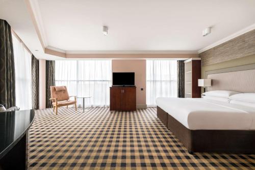 ニューカッスル・アポン・タインにあるダブルツリー バイ ヒルトン ホテルニューカッスル インターナショナルエアポートのベッドとテレビが備わるホテルルームです。