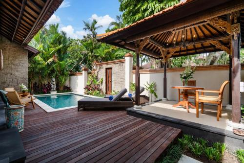 a wooden deck with a pool and a house at Svarga Bebek Villas in Ubud
