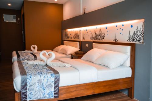 two beds in a hotel room with swans on them at Privada Villa Siargao in General Luna
