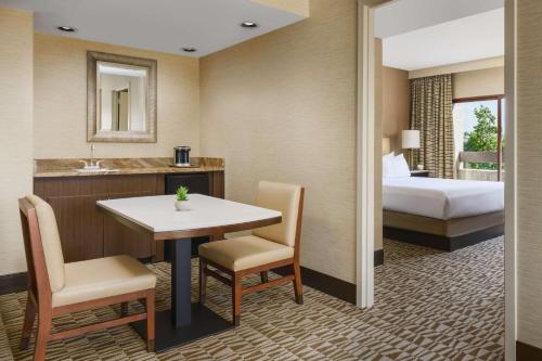 a hotel room with a bed and a table and chairs at Hilton Phoenix Airport in Phoenix