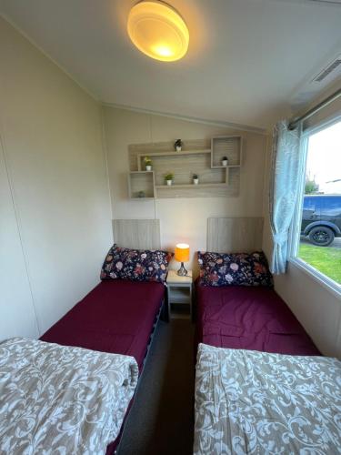 małą sypialnię z 2 łóżkami w przyczepie kempingowej w obiekcie 8 Bed Sun Decked Caravan Unlimited High speed Wifi and fun at Seawick Holiday Park w mieście Clacton-on-Sea