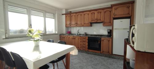 a kitchen with wooden cabinets and a white table with chairs at Xabarin Apartment in Abadín