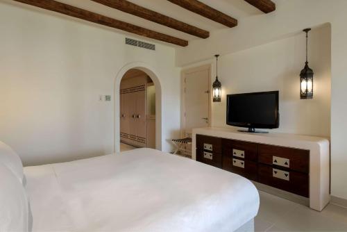 a bedroom with a bed and a television on a dresser at Hilton Marsa Alam Nubian Resort in Abu Dabab