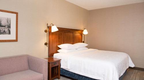 a hotel room with a bed and a chair at Hampton Inn & Suites Rochester/Victor in Victor