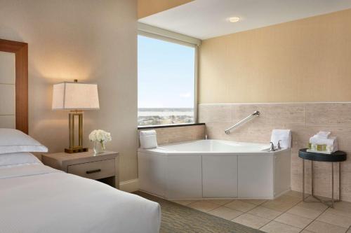 baño con bañera, cama y ventana en Hilton Suites Ocean City Oceanfront, en Ocean City