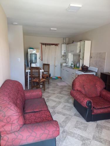 Carla في Puerto Santa Cruz: غرفة معيشة مع أريكة حمراء ومطبخ