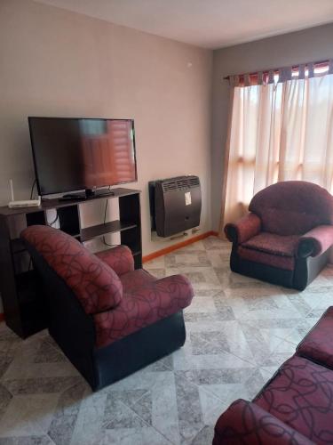 sala de estar con 2 sillas y TV de pantalla plana en Carla en Puerto Santa Cruz