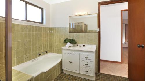 Un baño con bañera, lavabo y espejo. en Sylvia's at Currarong, en Currarong