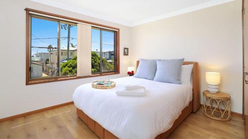 Un dormitorio con una cama blanca grande y una ventana en Sylvia's at Currarong, en Currarong
