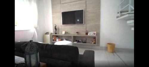 salon z kanapą i telewizorem z płaskim ekranem w obiekcie Quarto Privativo em Casa Linda w mieście Sorocaba