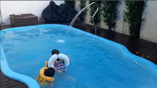 two people in a swimming pool with a water hose at Quarto Privativo em Casa Linda in Sorocaba