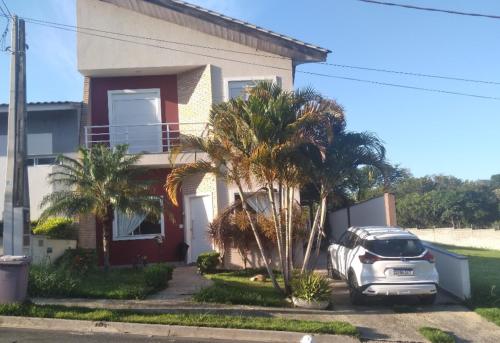 ソロカーバにあるQuarto Privativo em Casa Lindaのヤシの木が茂る家の前に停められた車