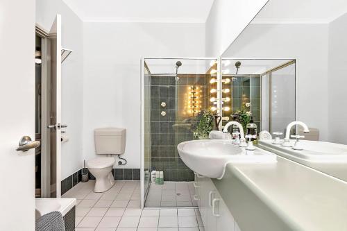 a white bathroom with two sinks and a toilet at Brompton Bliss - A Relaxed Northern Adelaide Retreat in Bowden