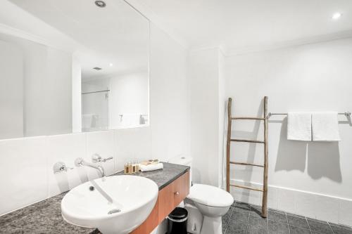 a white bathroom with a sink and a toilet at Belle Escapes Oceanview Suite 11 Alamanda Palm Cove in Palm Cove