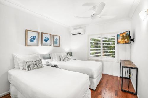 a white room with two beds and a window at Belle Escapes Oceanview Suite 11 Alamanda Palm Cove in Palm Cove