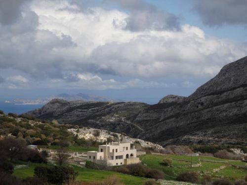 a house in a field with mountains in the background at Pera Horio House in Apeiranthos