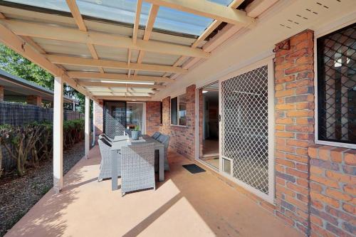 a patio with a brick wall and a wooden pergola at Shoreline House in Bargara