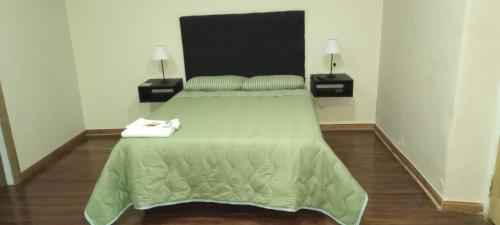 una camera da letto con un grande letto verde con due lampade di Hostal Adelita a Moisés Ville