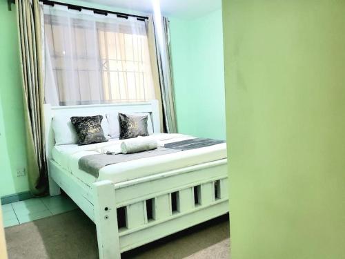 a white bed in a room with a window at SwanLakeview3br, Wi-Fi, Netflix, Balcony, Sunset. in Kisumu