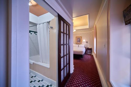 a corridor of a hotel room with a bed and a bathroom at The Bedford Regency Hotel in Victoria