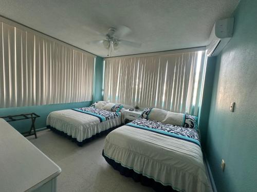 - 2 lits dans une chambre aux murs bleus et aux fenêtres dans l'établissement Aca life, à Acapulco