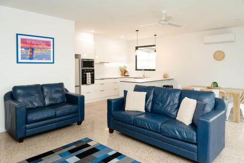 a living room with two blue couches and a kitchen at Apostle Escape in Port Campbell