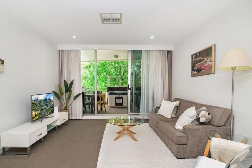a living room with a couch and a tv at Warm Waves - Beach Pool Home in Glenelg