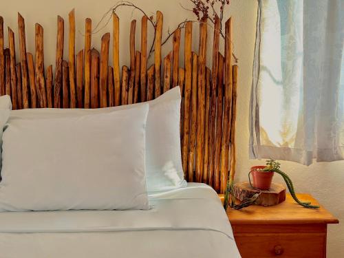 a bed with a wooden headboard and a white pillow at Hotel Jaiba Mahahual - Adults Only in Mahahual