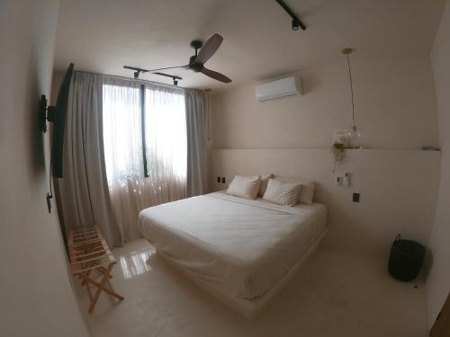 a bedroom with a white bed and a window at Casa Hood By the Sea in Holbox Island