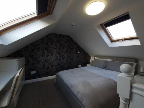 a attic bedroom with a bed and two windows at J's House in Nottingham