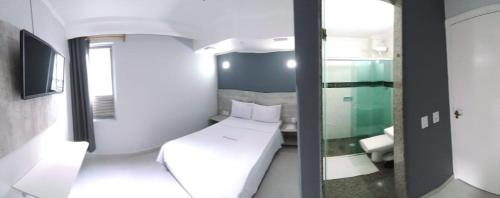 Habitación pequeña con cama y espejo. en Hotel Phizalis en São Caetano do Sul