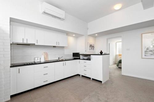 a white kitchen with white cabinets and appliances at Beach Retreat Apartment A in Frankston