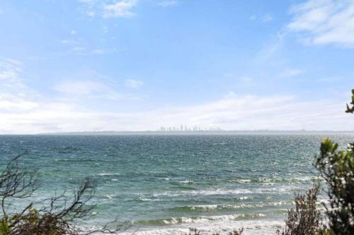 a view of the ocean with a city in the distance at Beach Retreat Apartment A in Frankston