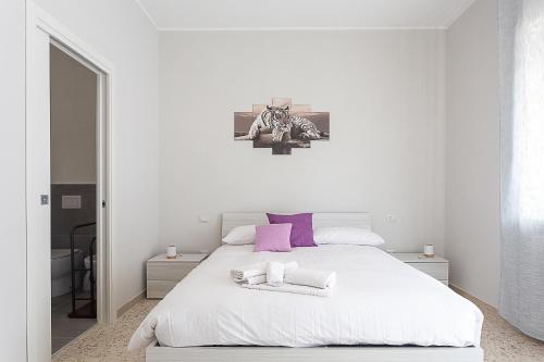 una camera bianca con un grande letto bianco con cuscini viola di [Leo's House] smart Tv & Wi-Fi a Campobasso