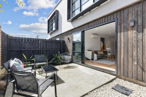 a patio with black and white furniture in front of a house at Peaceful Elegant Designated Park King Bed in Christchurch
