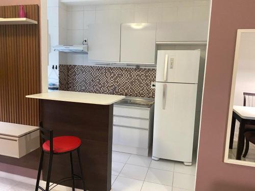 a kitchen with a white refrigerator and a red stool at Apartamento Aconchegante in Porto Alegre