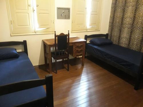 um quarto com 2 camas, uma secretária e uma mesa em Casa Patrimônio Histórico - Centro de Uberaba em Uberaba