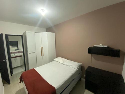 a small bedroom with a bed and a white cabinet at Apartamento Aconchegante in Porto Alegre