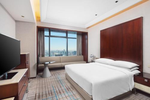 sypialnia z dużym białym łóżkiem i telewizorem w obiekcie Renaissance Shanghai Zhongshan Park Hotel w Szanghaju