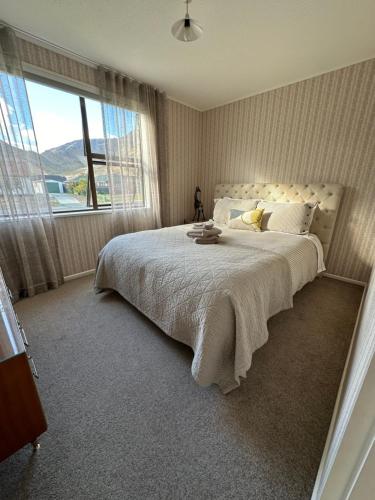 a bedroom with a large bed with a large window at Omara-more in Omarama