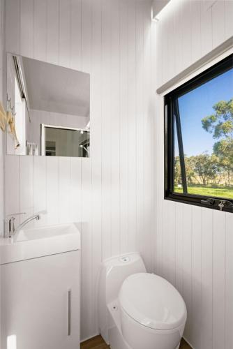 a white bathroom with a toilet and a window at Bush Retreat 2 by Tiny Away in Alberton West