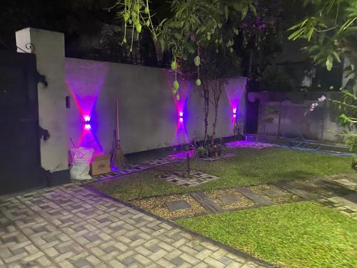 un jardín con luces moradas en la pared en Rose Villa Accommodation, en Seeduwa