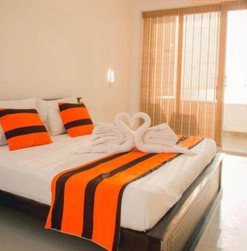 Una cama con una manta a rayas naranja y negra. en Rose Villa Accommodation, en Seeduwa