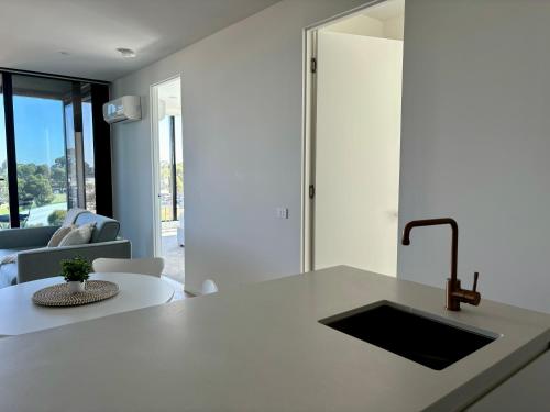 a kitchen with a sink and a living room at Skygarden Luxury Condo in Glen Waverley