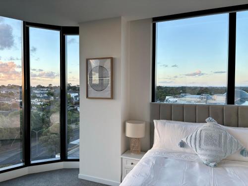 a bedroom with a bed and large windows at Skygarden Luxury Condo in Glen Waverley